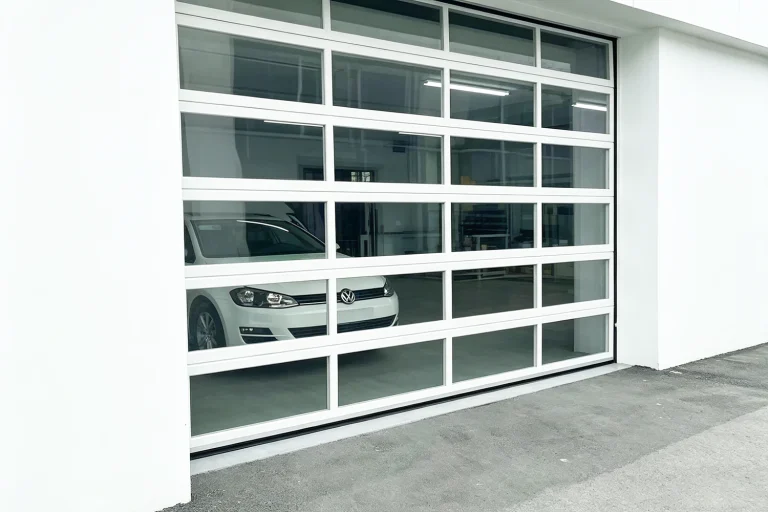 A modern white commercial all-window garage door with heavy-duty aluminum frames and clear vision panels, manufactured by ABX to maximize industrial daylighting for an automotive facility.