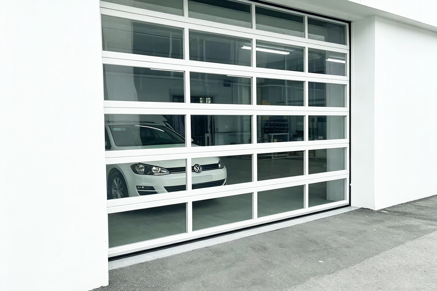 A modern white commercial all-window garage door with heavy-duty aluminum frames and clear vision panels, manufactured by ABX to maximize industrial daylighting for an automotive facility.