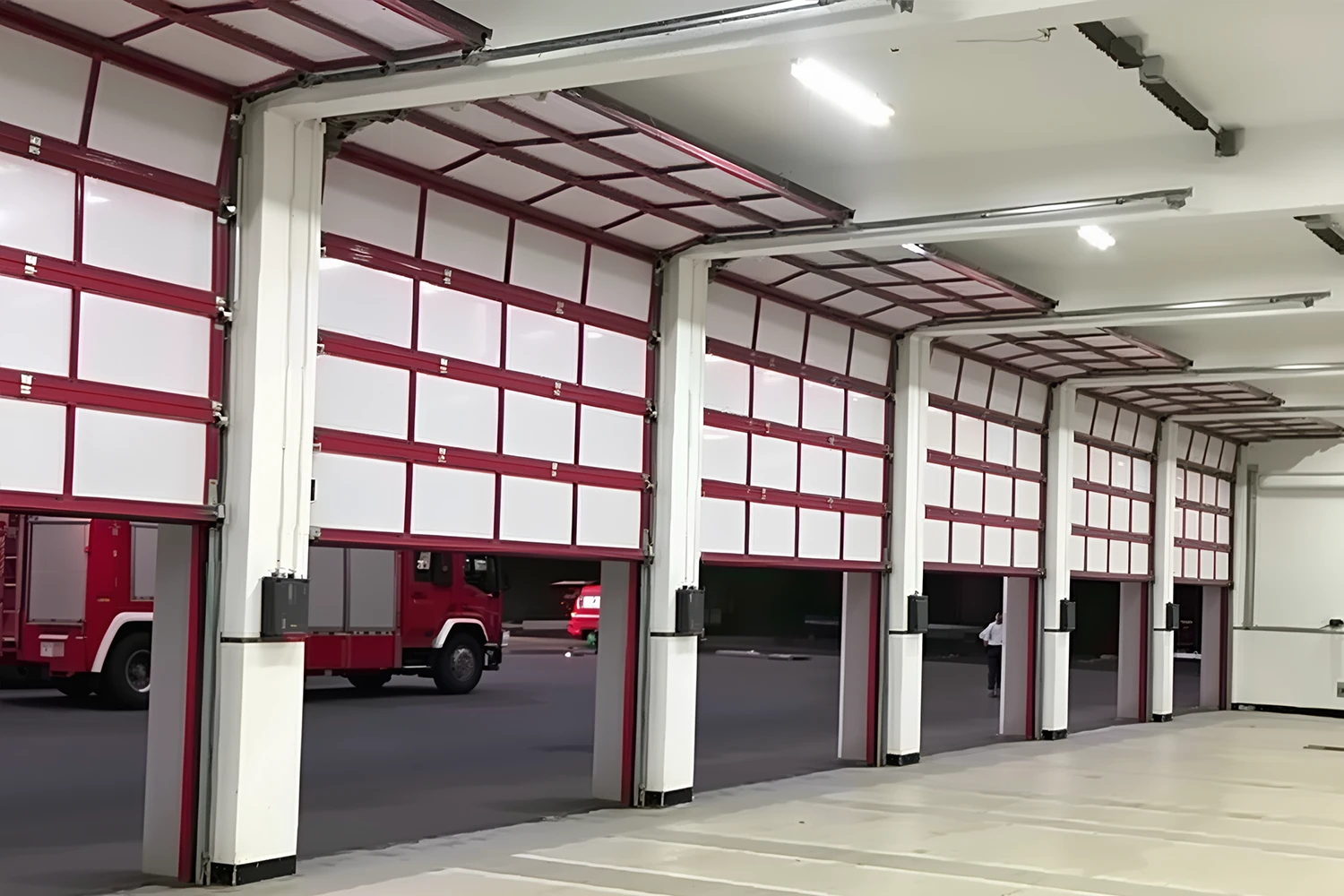 A row of heavy-duty commercial fire station doors installed in an emergency response facility. ABX OEM manufacturer engineers high-speed automatic solutions with power redundancy and CE/ISO compliance for government and wholesale projects.