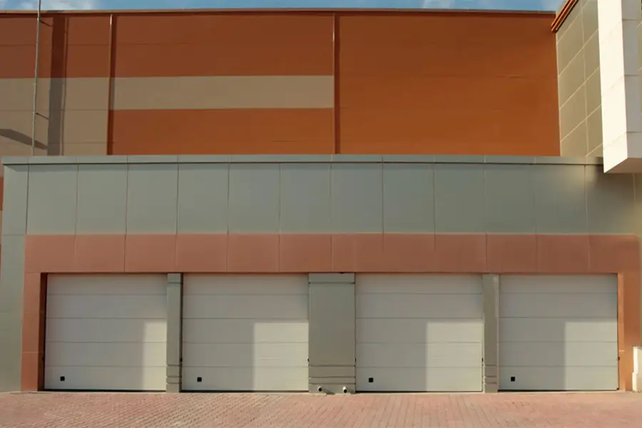 Multiple white sectional commercial sectional doors installed at a large industrial warehouse facility.